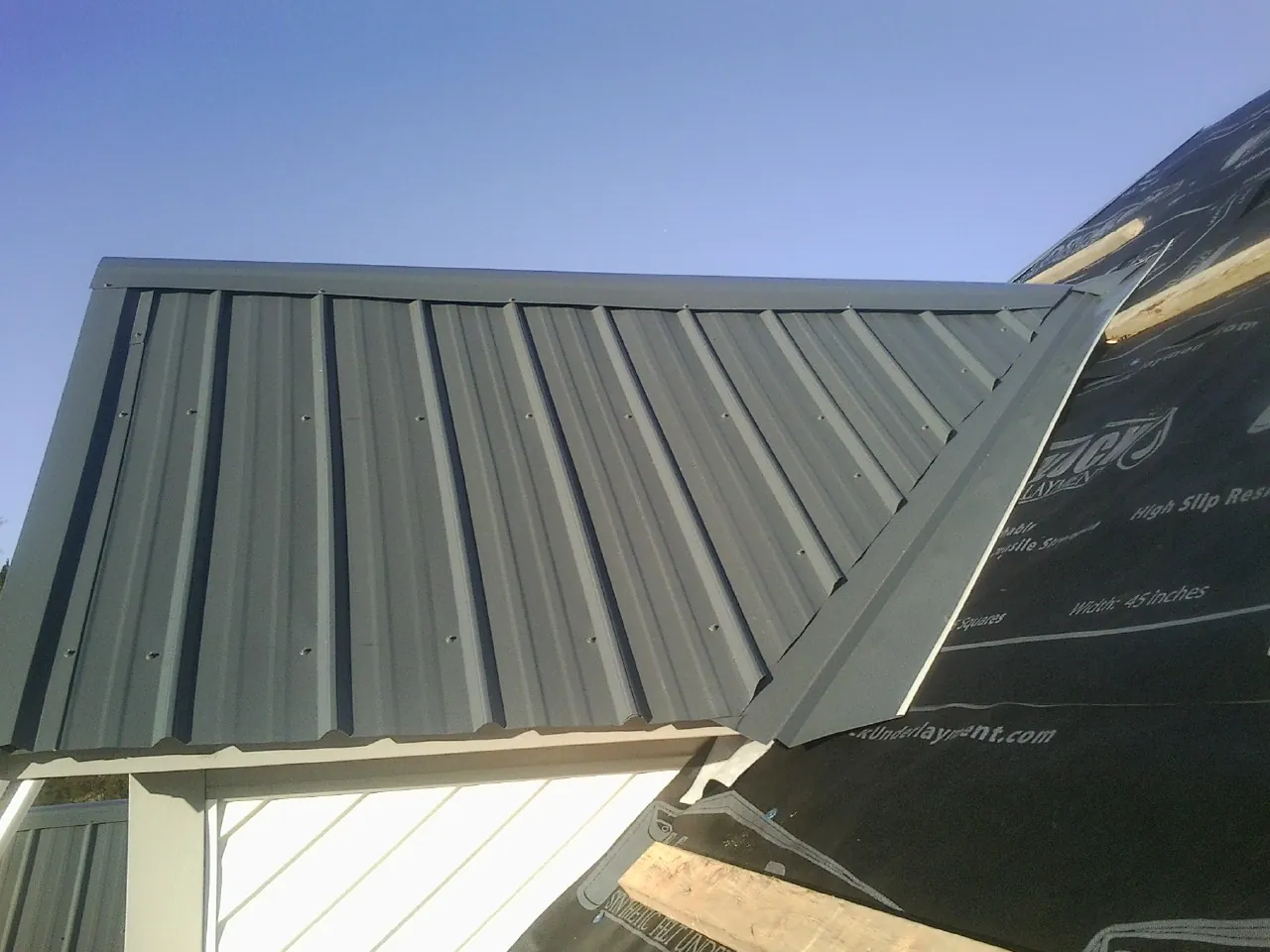 Gray metal roof panels going on over a garage gable in Branchville