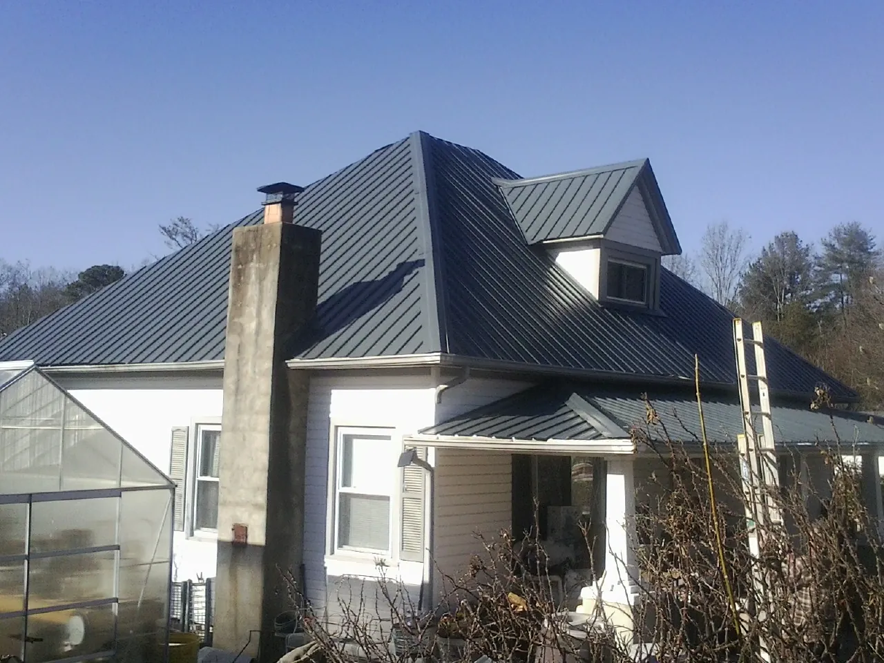 Dark blue standing seam metal roof on a white farmhouse with dormer — Slate & Tile Roof Repair by Roofing Brothers in Branchville