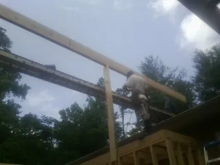 Carpenter setting a ridge beam over a new addition frame — Ice Dam Removal by Roofing Brothers in Branchville