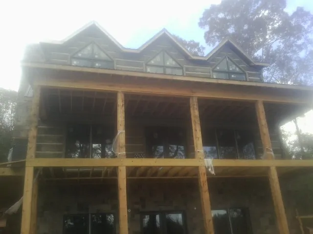 Dormers and porch framing on a large log home under construction — Roof Coating work by our crew in Branchville