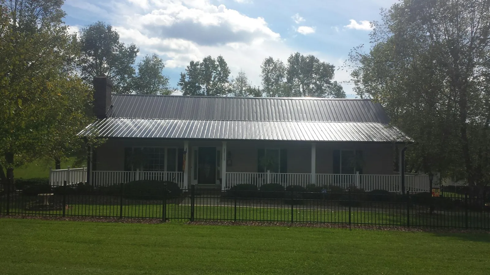 Gray metal roof on a brick ranch with a full width front porch — Gutter Guard Installation work by our crew in Branchville