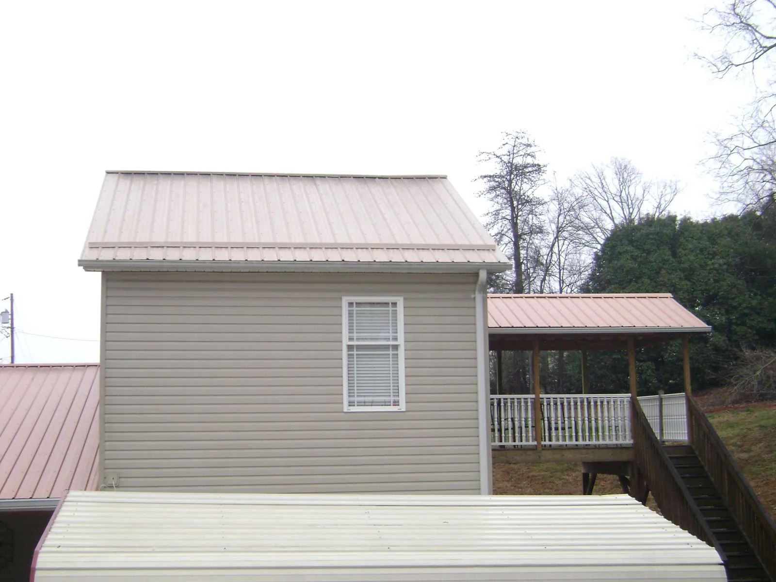 Tan metal roofs on a two story addition and attached porch, from a Roof Replacement job in Branchville